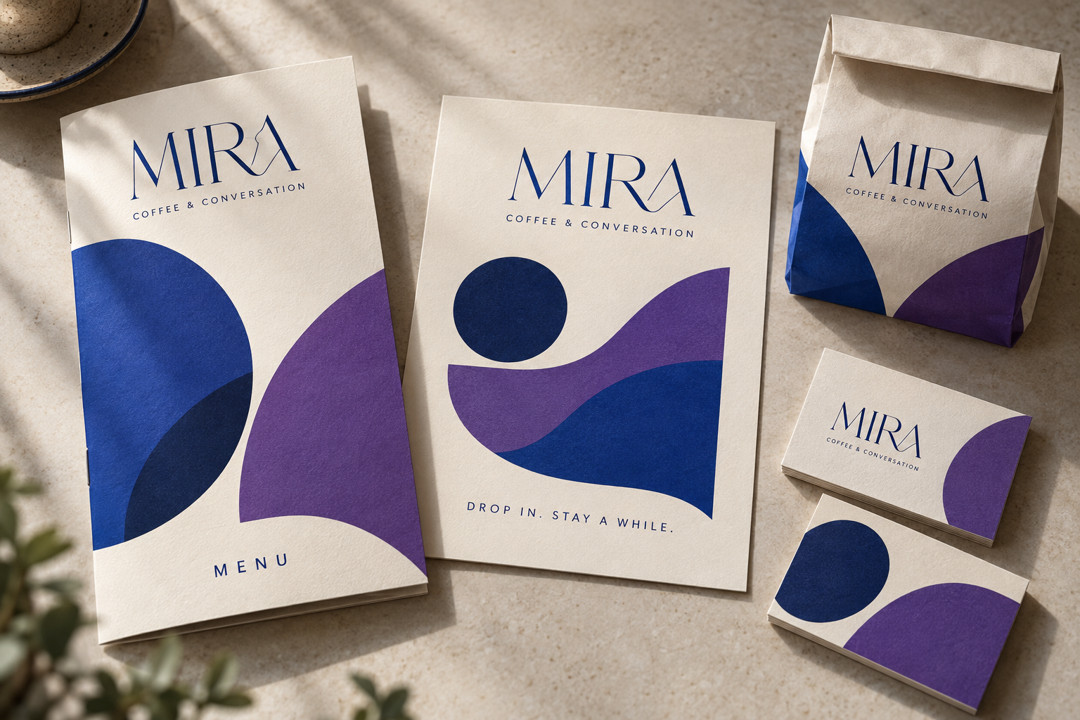 Fictional MIRA coffee concept showing a menu, promotional flyer, business cards and paper packaging in cobalt and purple